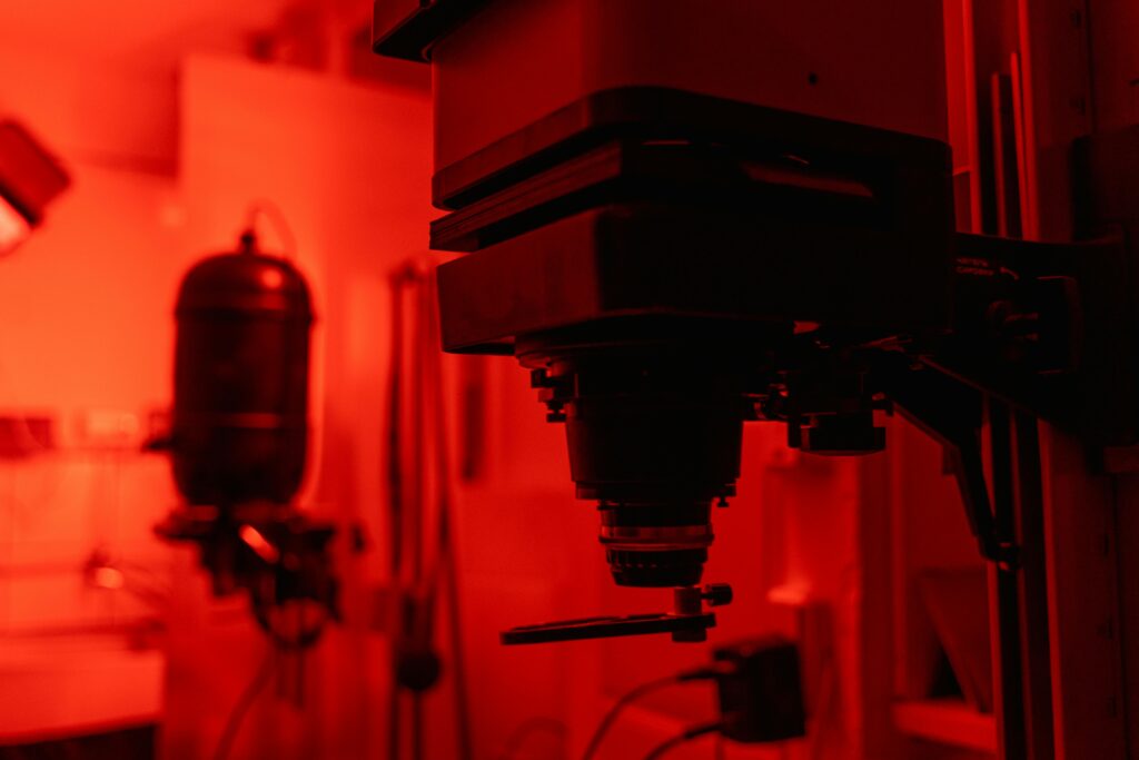 Dimly lit photography darkroom showing classic film developing equipment and red lighting.