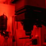 Dimly lit photography darkroom showing classic film developing equipment and red lighting.